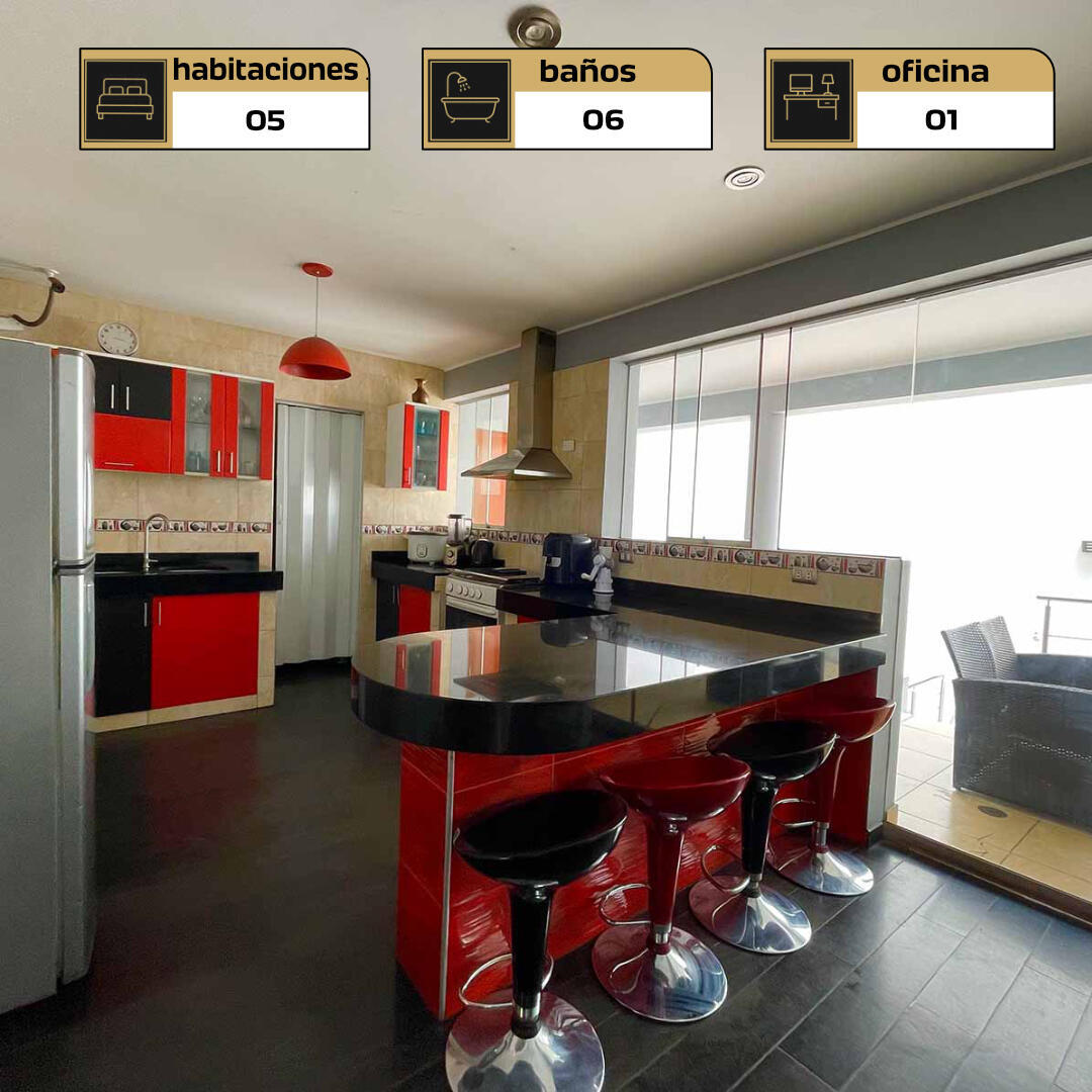 Cocina estilo americano con mesa de granito, campana extractora y mampara hacia la terraza en casa de La Molina